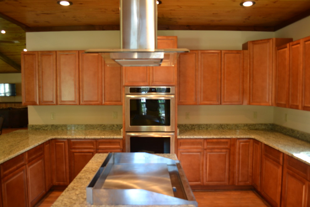 Mid-sized mountain style u-shaped medium tone wood floor kitchen photo in Atlanta with raised-panel cabinets, brown cabinets, granite countertops, stainless steel appliances and an island