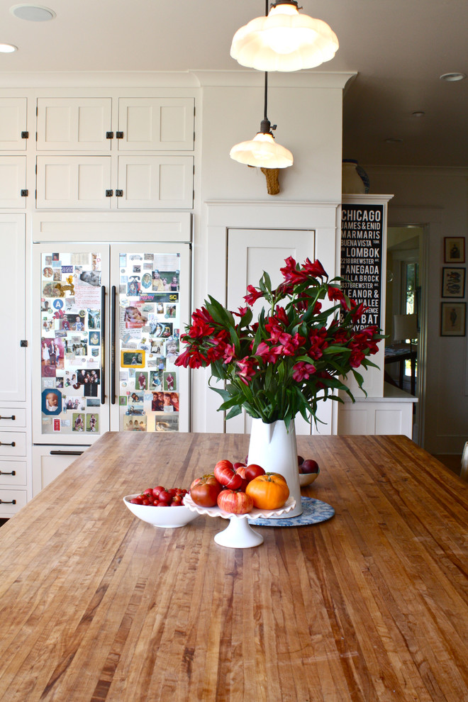 This is an example of a traditional kitchen in San Francisco with wood benchtops, white cabinets and panelled appliances.