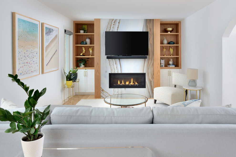 This is an example of a mid-sized midcentury open concept living room in Toronto with white walls, light hardwood floors, a standard fireplace, a stone fireplace surround, a wall-mounted tv and beige floor.