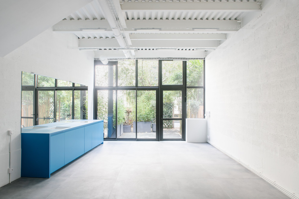 Foto di una cucina moderna di medie dimensioni con lavello sottopiano, ante lisce, ante blu, top in superficie solida, paraspruzzi a specchio, elettrodomestici da incasso, pavimento con piastrelle in ceramica, pavimento grigio, top blu e travi a vista
