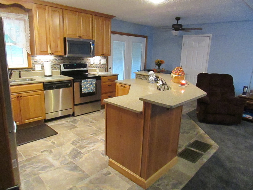Home design - mid-sized transitional l-shaped ceramic tile home design idea with a double-bowl sink, raised-panel cabinets, light wood cabinets, quartz countertops, multicolored backsplash, mosaic tile backsplash, stainless steel appliances and an island