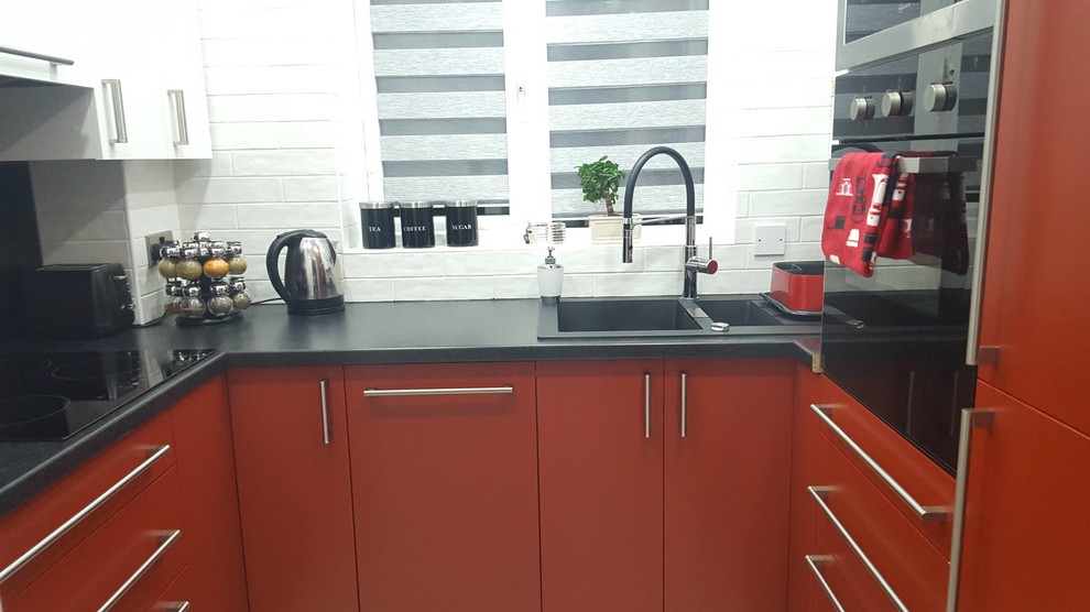 Photo of a small contemporary u-shaped separate kitchen in London with flat-panel cabinets, red cabinets, laminate benchtops, multi-coloured splashback, glass sheet splashback, panelled appliances, laminate floors and no island.