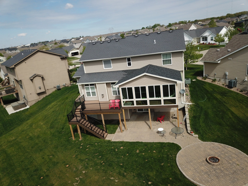 Example of a large backyard second story metal railing deck design with a roof extension