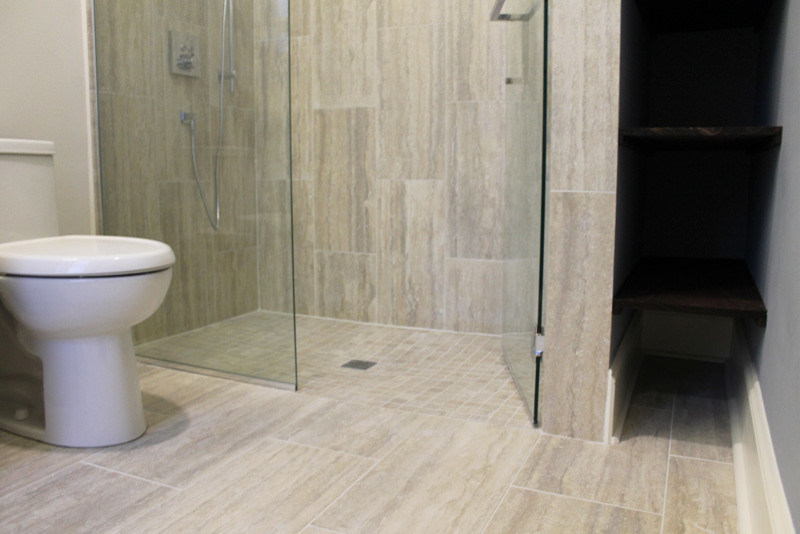 This is an example of a mid-sized modern master bathroom in Chicago with dark wood cabinets, a curbless shower, a one-piece toilet, gray tile, ceramic tile, white walls, ceramic floors, engineered quartz benchtops, grey floor, a hinged shower door, shaker cabinets, an undermount sink and white benchtops.