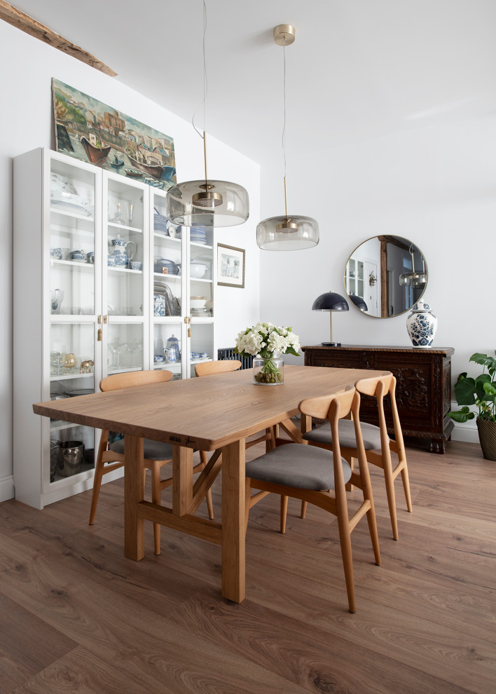 Inspiration pour une salle à manger ouverte sur le salon nordique de taille moyenne avec un mur blanc, sol en stratifié, un sol marron et poutres apparentes.