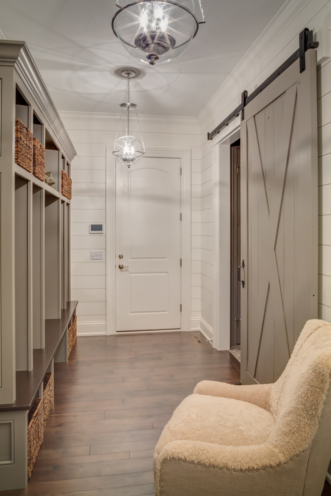 Photo of a mid-sized country mudroom in Cleveland with white walls, dark hardwood floors and a dark wood front door.