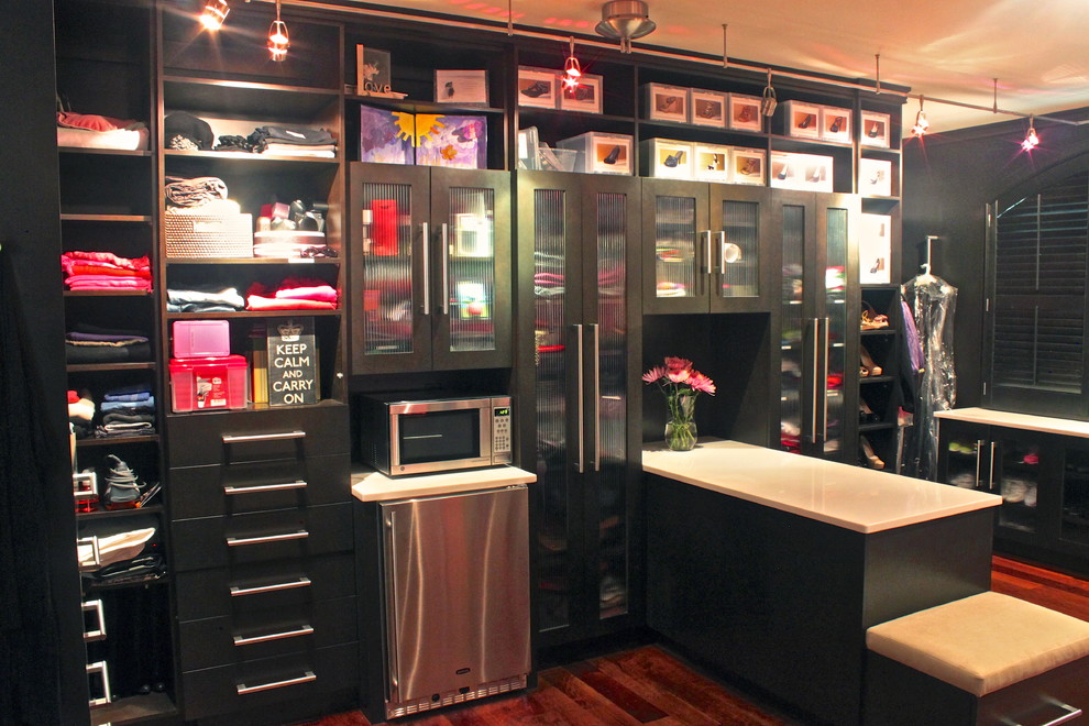 Photo of a mid-sized contemporary storage and wardrobe in New York with glass-front cabinets.