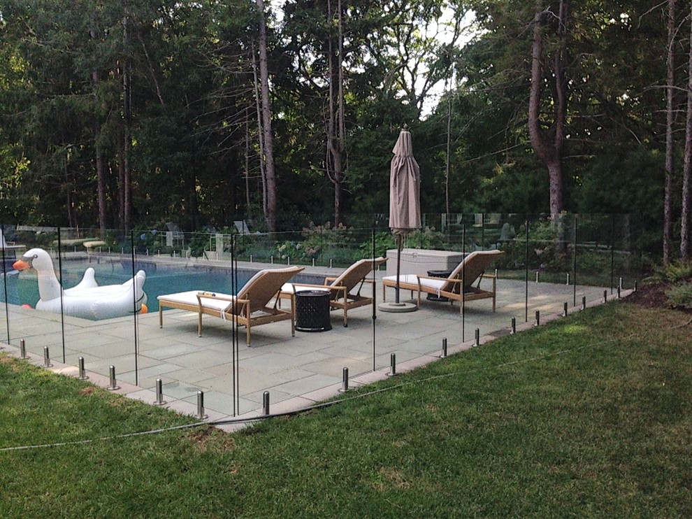 Inspiration for a mid-sized contemporary backyard pool in New York with natural stone pavers.