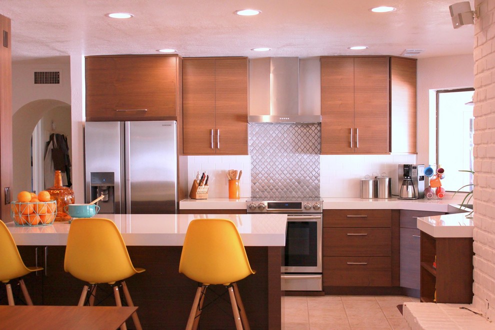 This is an example of a mid-sized midcentury u-shaped eat-in kitchen in Phoenix with flat-panel cabinets, quartz benchtops, stainless steel appliances, with island, medium wood cabinets, white splashback, an undermount sink, subway tile splashback and ceramic floors.