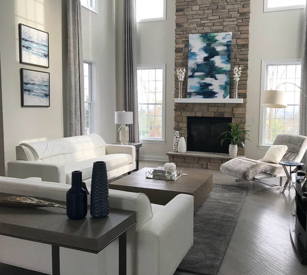 Large transitional formal enclosed living room in Philadelphia with grey walls, light hardwood floors, a standard fireplace, a stone fireplace surround, no tv and grey floor.
