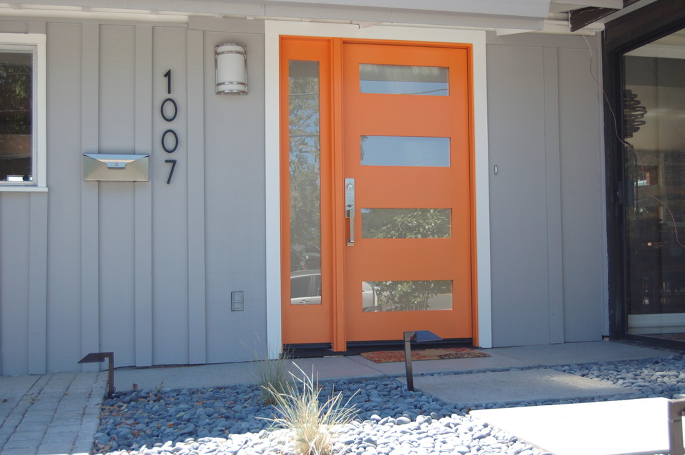 This is an example of a mid-sized transitional front door in San Francisco with grey walls, a single front door and an orange front door.