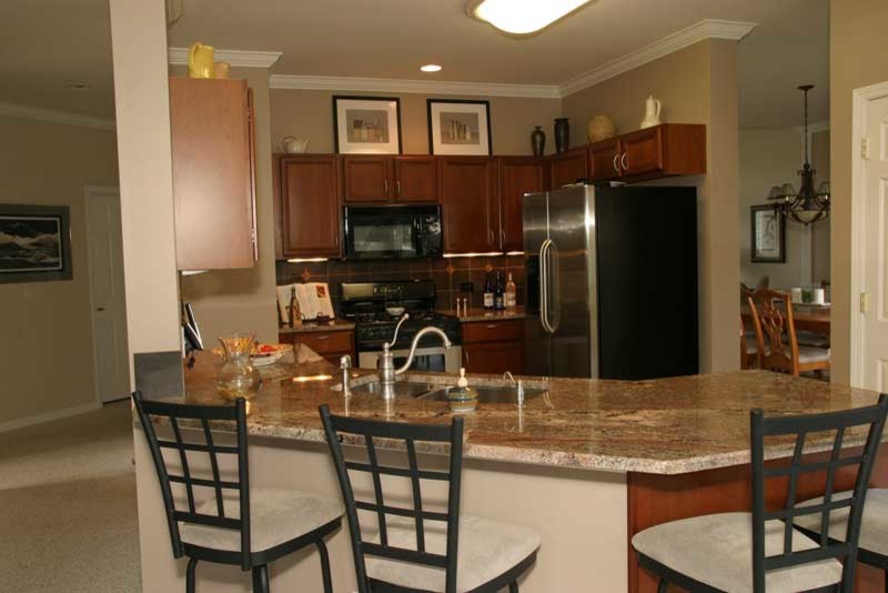 Transitional u-shaped medium tone wood floor kitchen pantry photo in Chicago with raised-panel cabinets, medium tone wood cabinets and granite countertops