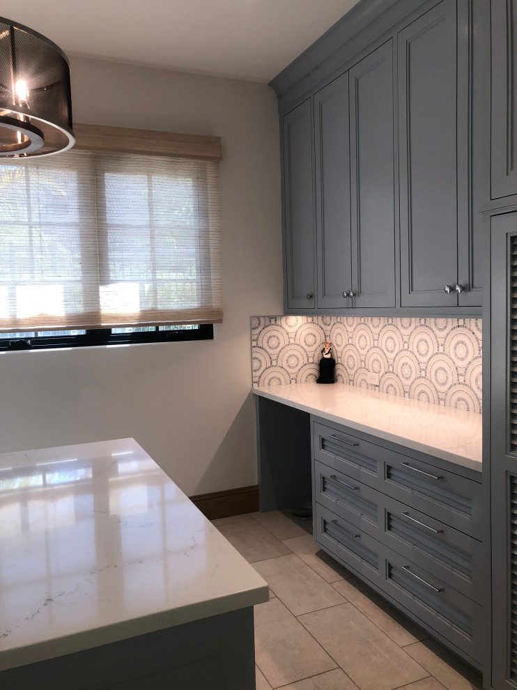 Inspiration for a large transitional u-shaped dedicated laundry room in Other with a farmhouse sink, shaker cabinets, blue cabinets, quartz benchtops, blue splashback, mosaic tile splashback, white walls, porcelain floors, a side-by-side washer and dryer, grey floor and white benchtop.
