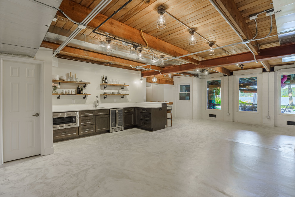 This is an example of a large industrial walk-out basement in Other with a home bar, white walls, white floors and exposed beams.