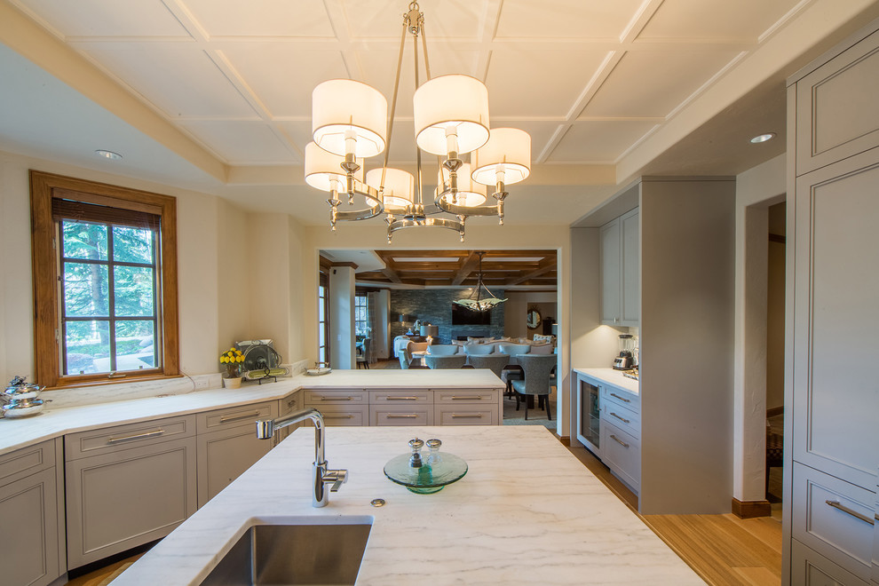 Photo of a large traditional u-shaped eat-in kitchen in Denver with an undermount sink, beaded inset cabinets, grey cabinets, marble benchtops, beige splashback, marble splashback, panelled appliances, medium hardwood floors, with island, brown floor, multi-coloured benchtop and coffered.