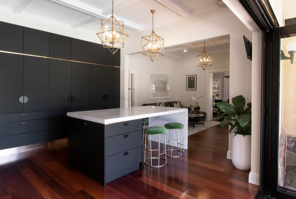 Photo of a large contemporary u-shaped open plan kitchen in Adelaide with an undermount sink, recessed-panel cabinets, black cabinets, quartz benchtops, metallic splashback, black appliances, medium hardwood floors, with island, white benchtop and coffered.