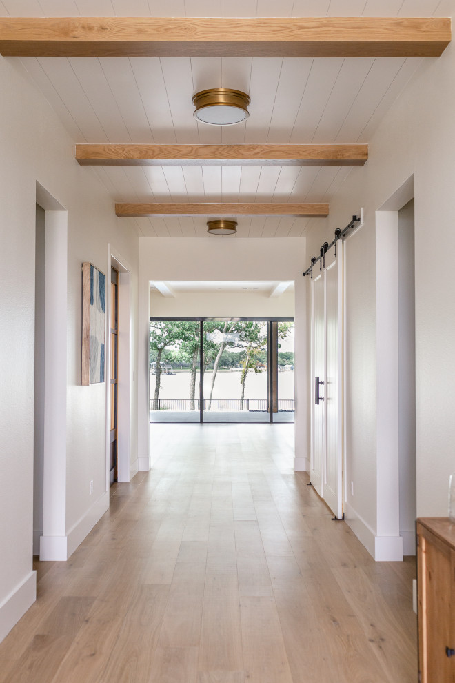 Large modern foyer in Dallas with white walls, light hardwood flooring and a timber clad ceiling.