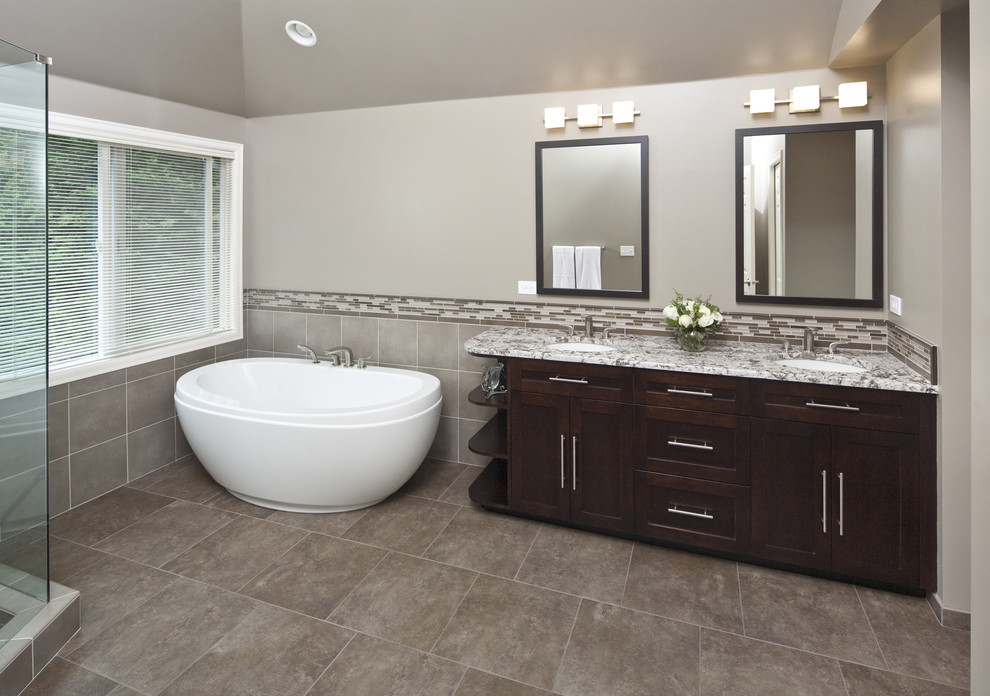 Photo of a large contemporary bathroom in Seattle with shaker cabinets, dark wood cabinets, a freestanding tub, a corner shower, beige tile, brown tile, gray tile, matchstick tile, grey walls, ceramic floors and an undermount sink.