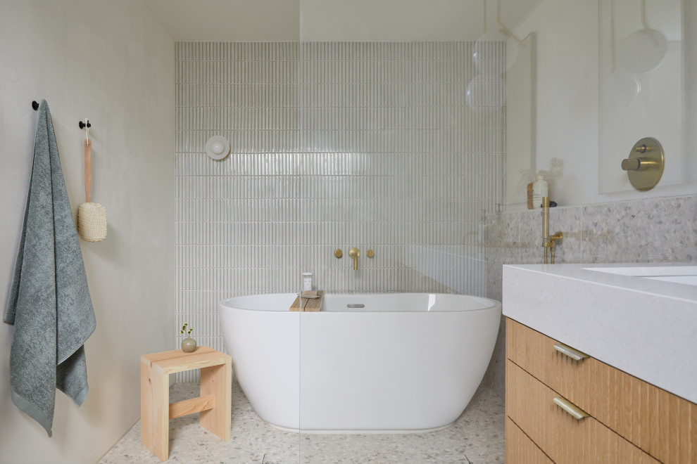 Photo of a small midcentury master bathroom in San Francisco with brown cabinets, a freestanding tub, a shower/bathtub combo, a wall-mount toilet, white tile, ceramic tile, white walls, terrazzo floors, an undermount sink, engineered quartz benchtops, white floor, an open shower, white benchtops, a double vanity and a floating vanity.