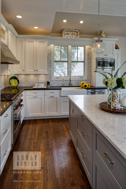 Design ideas for a mid-sized traditional kitchen in Chicago with a farmhouse sink, shaker cabinets, white cabinets, quartz benchtops, grey splashback, stone tile splashback, stainless steel appliances, medium hardwood floors and with island.