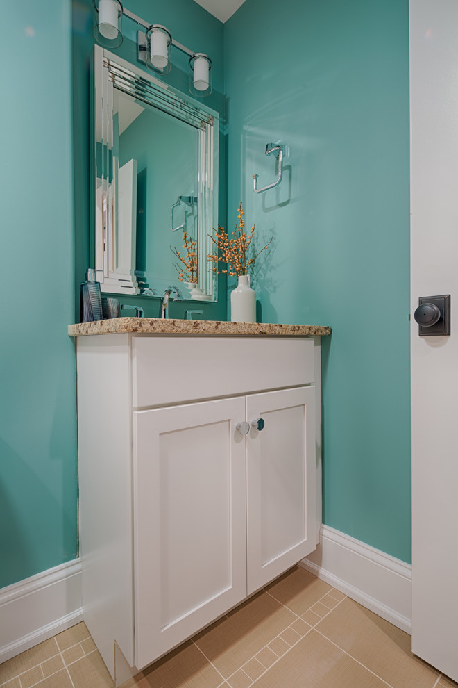 Photo of a mid-sized transitional powder room in Philadelphia with recessed-panel cabinets, white cabinets, granite benchtops, beige tile, a two-piece toilet, an undermount sink, ceramic floors and blue walls.