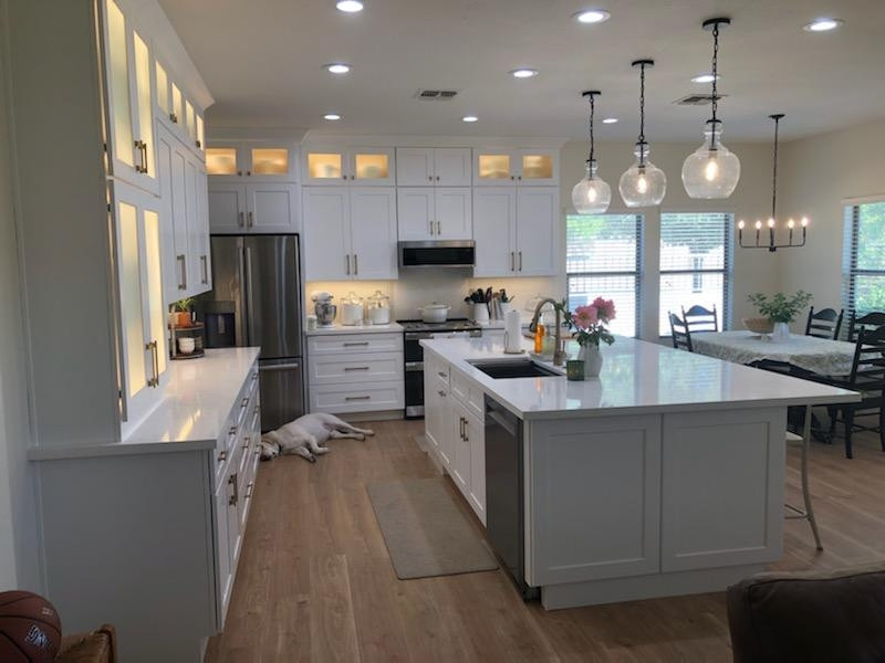 Design ideas for a large modern l-shaped kitchen pantry in Phoenix with a single-bowl sink, shaker cabinets, white cabinets, engineered stone countertops, stainless steel appliances, light hardwood flooring, an island, brown floors and white worktops.