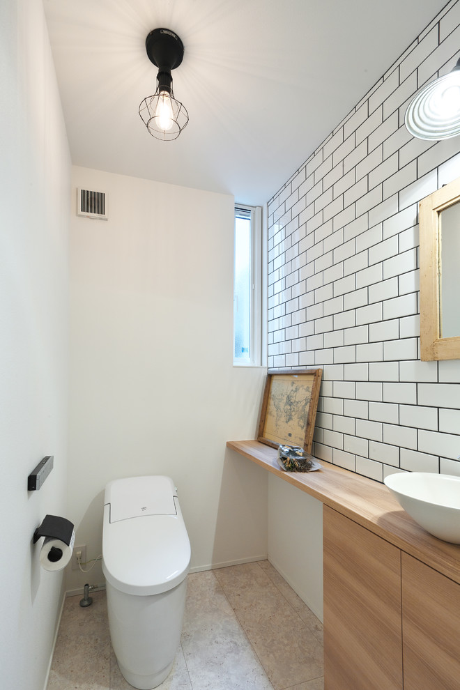 Small industrial powder room in Other with flat-panel cabinets, light wood cabinets, white tile, subway tile, white walls, vinyl floors, a vessel sink, wood benchtops, grey floor and white benchtops.