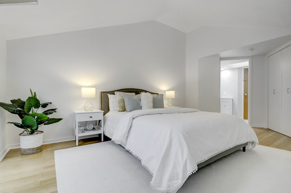 Medium sized farmhouse master bedroom in Montreal with white walls, light hardwood flooring and a vaulted ceiling.