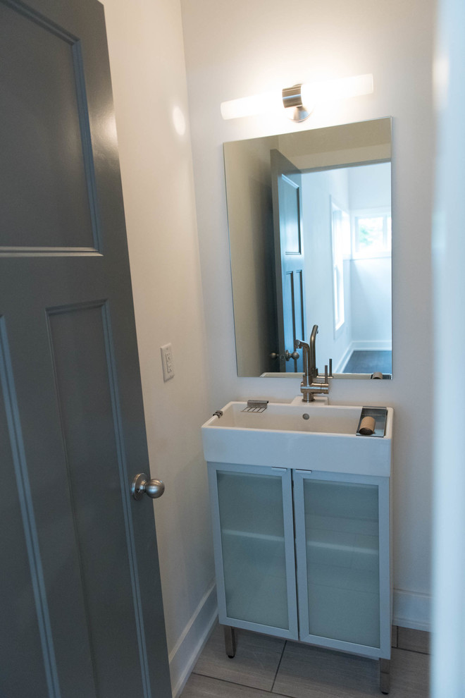 Mid-sized contemporary 3/4 bathroom in Indianapolis with glass-front cabinets, grey cabinets, a two-piece toilet, white walls, solid surface benchtops, an alcove tub, a shower/bathtub combo, white tile, subway tile, slate floors, an integrated sink, grey floor and a shower curtain.