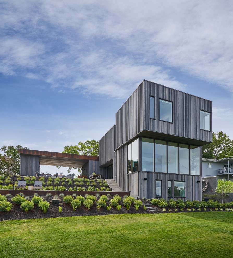 Imagen de fachada de casa gris minimalista de tamaño medio de tres plantas con tejado plano y panel y listón