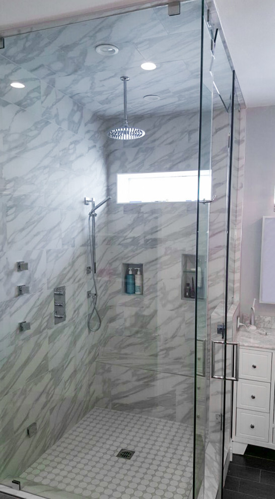 На фото: главная ванная комната среднего размера в викторианском стиле с фасадами с выступающей филенкой, белыми фасадами, отдельно стоящей ванной, угловым душем, унитазом-моноблоком, белой плиткой, мраморной плиткой, белыми стенами, полом из керамогранита, врезной раковиной, мраморной столешницей, серым полом, душем с распашными дверями, белой столешницей, нишей, тумбой под две раковины и напольной тумбой с