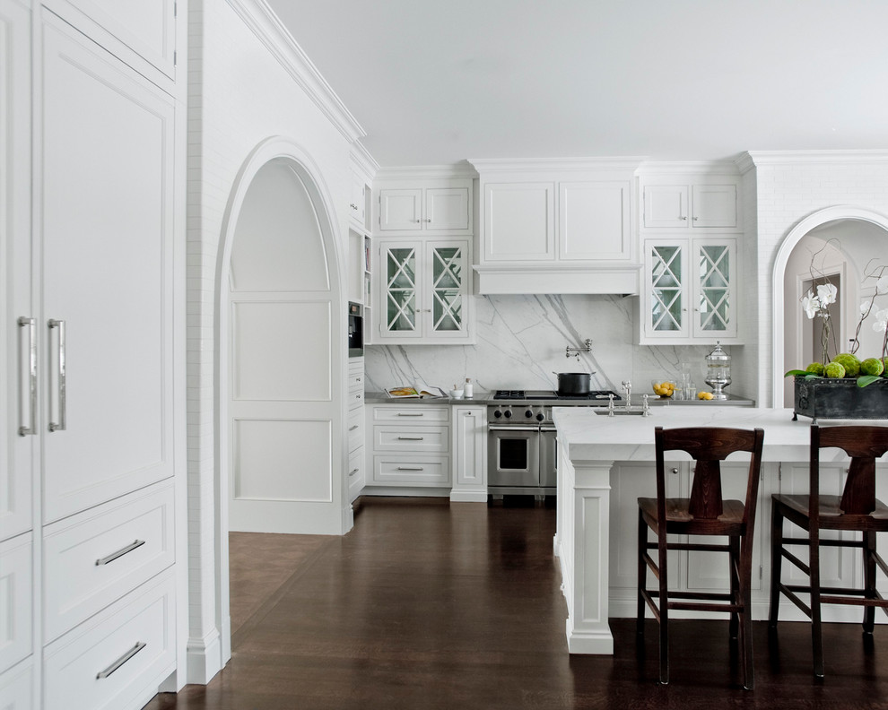 Large elegant u-shaped dark wood floor kitchen photo in Detroit with an undermount sink, recessed-panel cabinets, white cabinets, marble countertops, white backsplash, paneled appliances, an island, white walls and marble backsplash