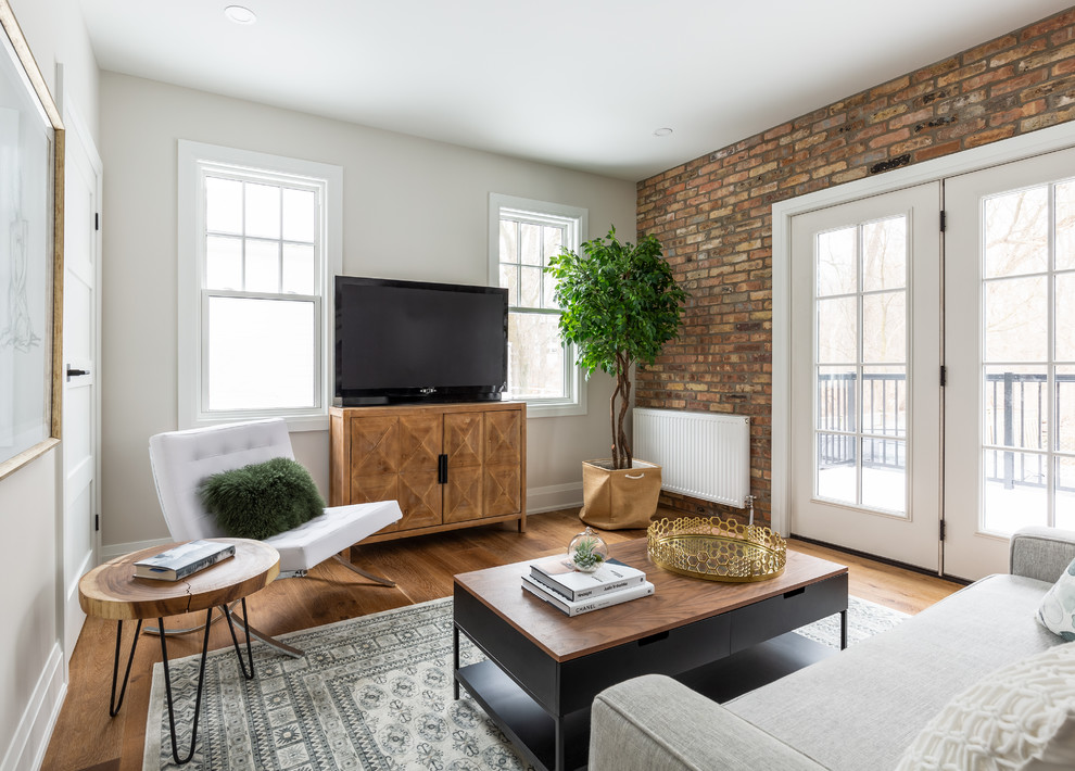 Inspiration for a small industrial living room in Toronto with medium hardwood floors, white walls, no fireplace, a freestanding tv and brown floor.