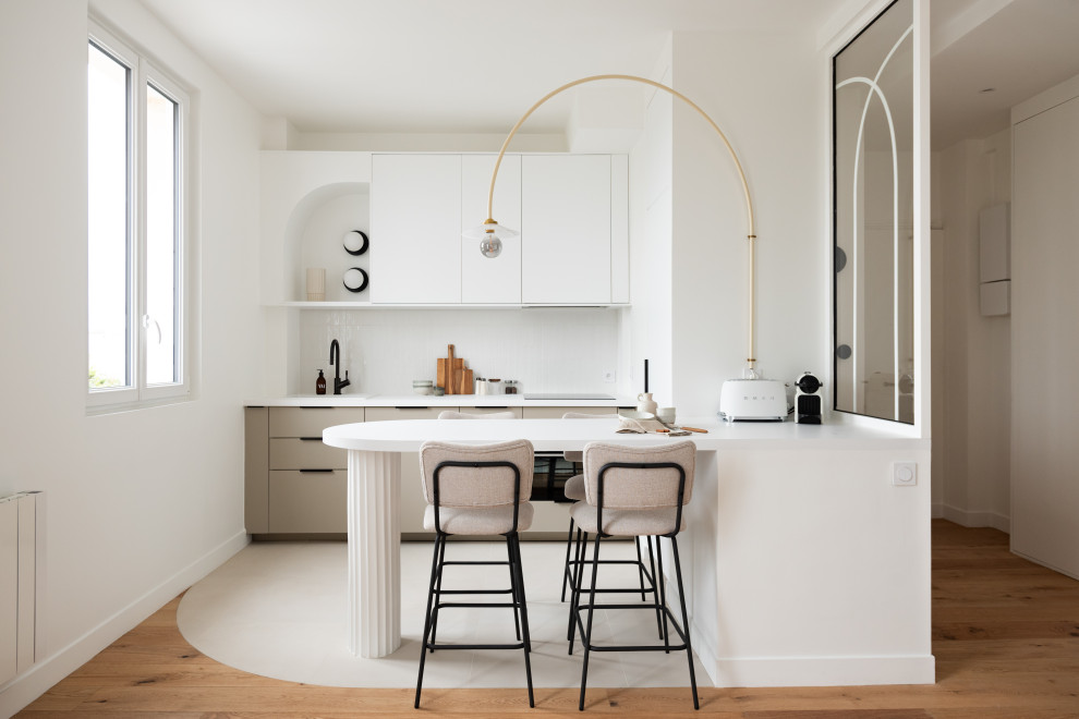 Réalisation d'une cuisine parallèle minimaliste avec un placard à porte plane, des portes de placard grises, une crédence blanche, une péninsule, un sol blanc et un plan de travail blanc.
