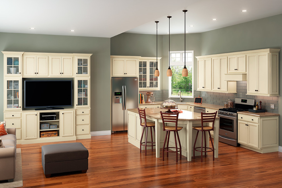Example of a mid-sized transitional l-shaped medium tone wood floor kitchen design in DC Metro with an undermount sink, recessed-panel cabinets, yellow cabinets, quartz countertops, glass tile backsplash, stainless steel appliances and an island