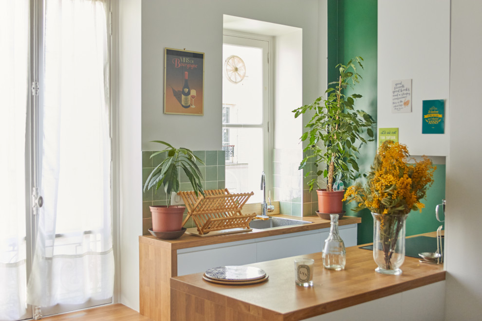Bild på ett mellanstort funkis beige beige kök, med en enkel diskho, luckor med profilerade fronter, vita skåp, laminatbänkskiva, grönt stänkskydd, stänkskydd i keramik, klinkergolv i keramik och beiget golv
