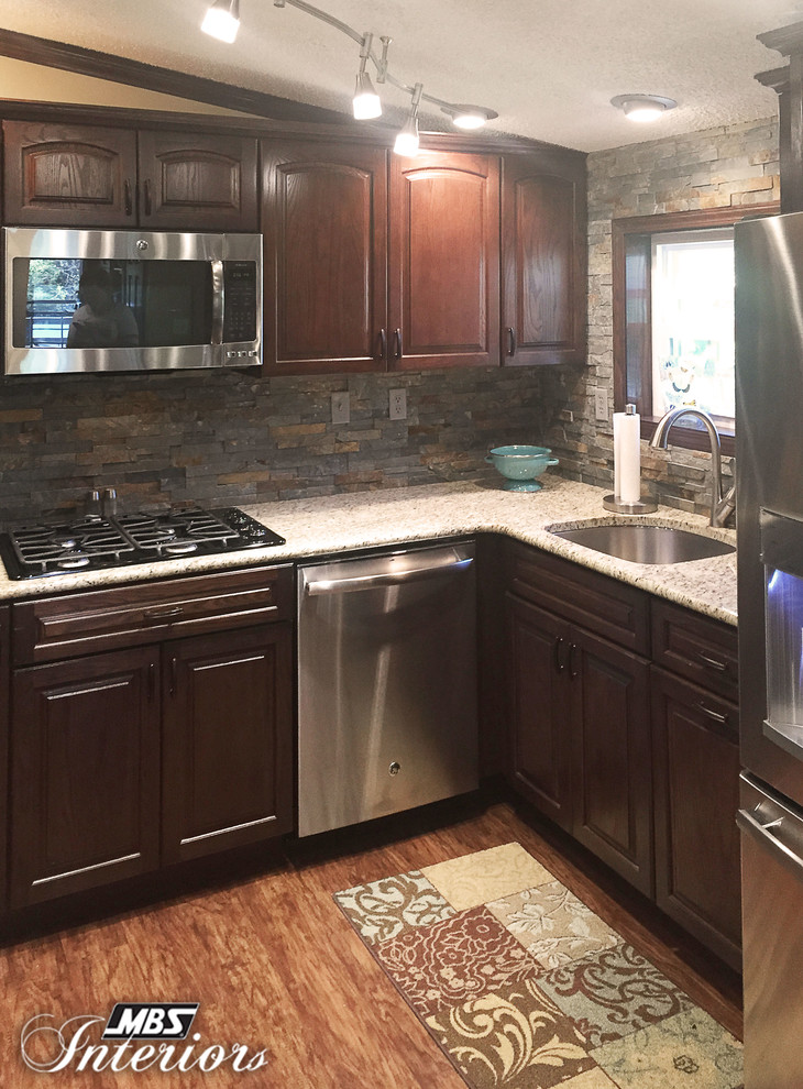 Example of a small transitional u-shaped medium tone wood floor enclosed kitchen design with an undermount sink, dark wood cabinets, gray backsplash, stone tile backsplash, stainless steel appliances and no island