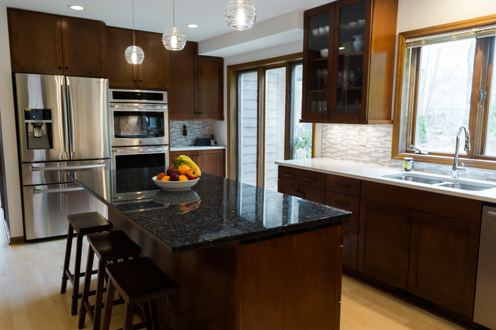 Example of a large transitional l-shaped light wood floor eat-in kitchen design with an undermount sink, shaker cabinets, dark wood cabinets, quartz countertops, gray backsplash, matchstick tile backsplash, stainless steel appliances and an island