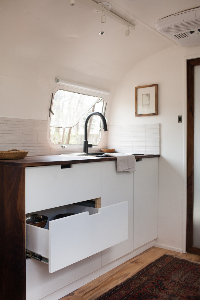 Inspiration for a modern kitchen in San Francisco with white cabinets, wood benchtops, white splashback and ceramic splashback.