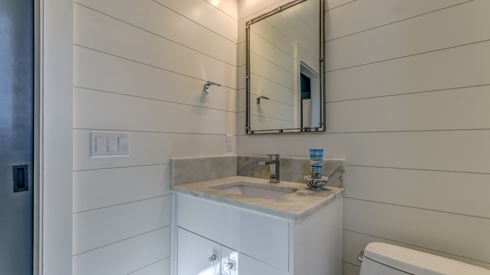Inspiration for a mid-sized beach style 3/4 bathroom in Miami with flat-panel cabinets, white cabinets, marble benchtops, multi-coloured benchtops, an alcove shower, a two-piece toilet, white walls and an undermount sink.