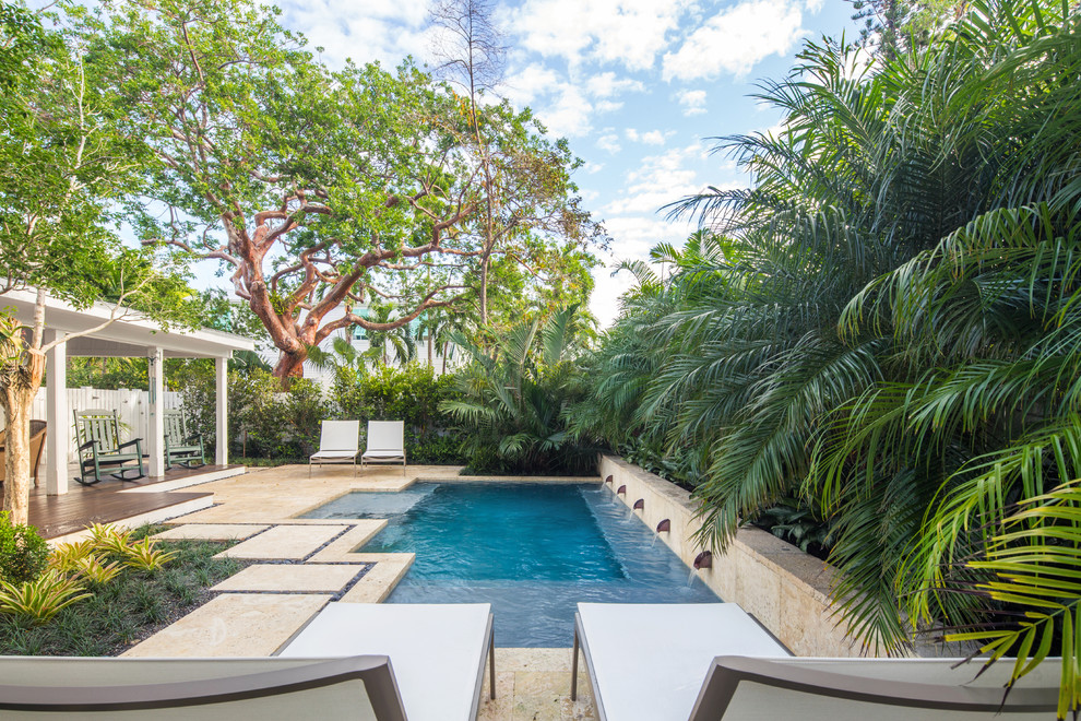 Mid-sized beach style backyard custom-shaped pool in Miami with natural stone pavers.