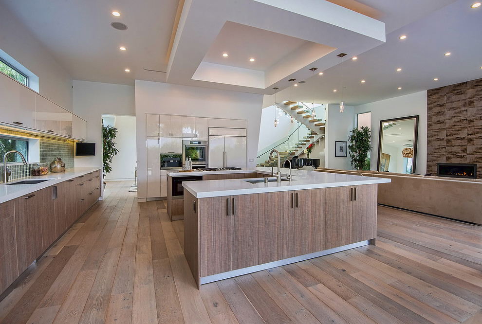 Inspiration for a mid-sized modern l-shaped open plan kitchen in Los Angeles with an undermount sink, flat-panel cabinets, medium wood cabinets, solid surface benchtops, stainless steel appliances, medium hardwood floors, with island, beige floor, green splashback and porcelain splashback.