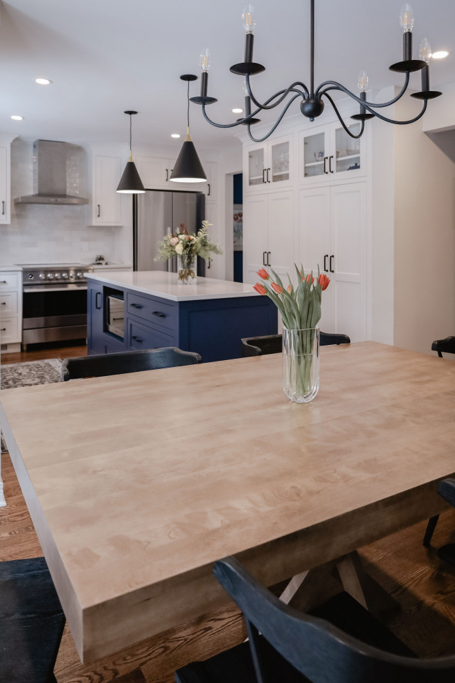 Eat-in kitchen - small transitional u-shaped medium tone wood floor and brown floor eat-in kitchen idea in Ottawa with an undermount sink, shaker cabinets, white cabinets, quartz countertops, white backsplash, subway tile backsplash, stainless steel appliances, an island and white countertops