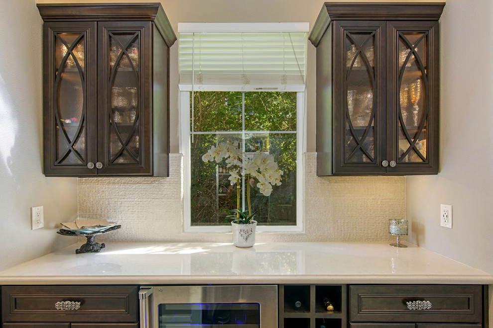 Inspiration for a large transitional l-shaped medium tone wood floor and brown floor open concept kitchen remodel in San Diego with recessed-panel cabinets, dark wood cabinets, quartz countertops, beige backsplash, travertine backsplash, paneled appliances and an island