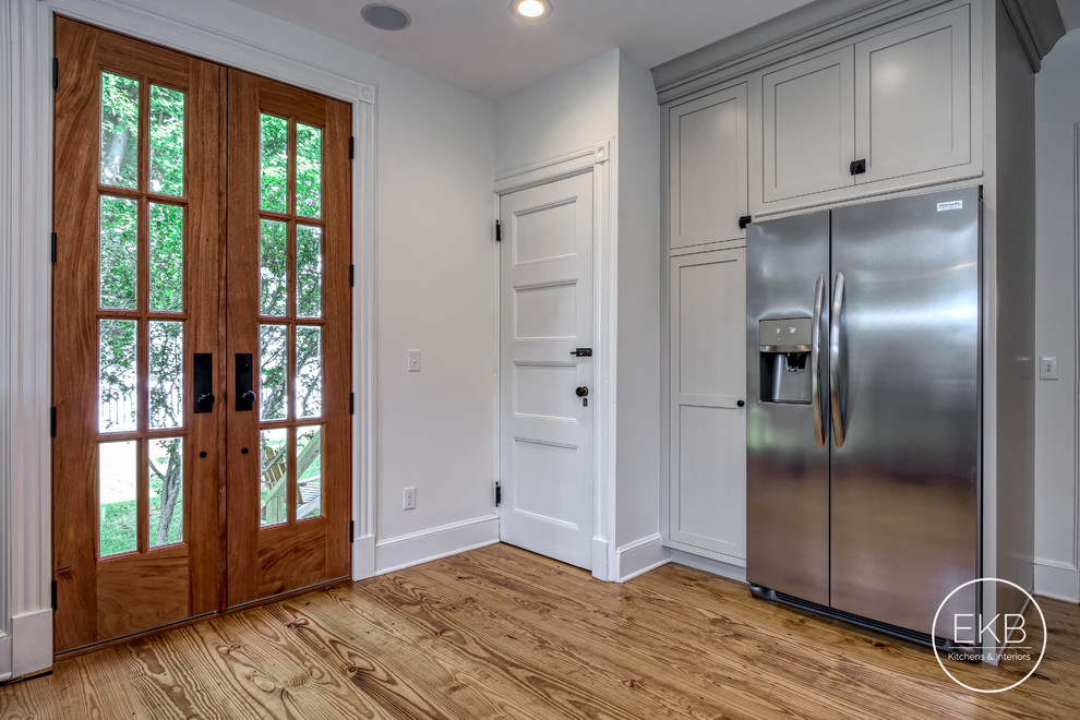 Photo of a mid-sized traditional u-shaped eat-in kitchen in New York with a farmhouse sink, shaker cabinets, grey cabinets, soapstone benchtops, white splashback, timber splashback, stainless steel appliances, medium hardwood floors, no island, brown floor and multi-coloured benchtop.