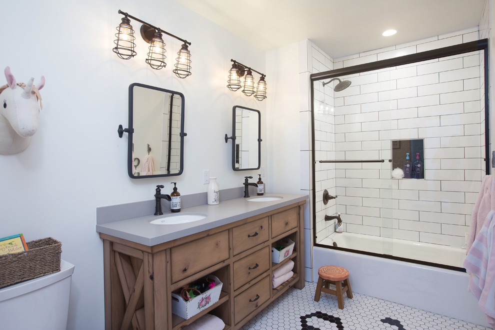 Photo of a mid-sized country kids bathroom in San Diego with flat-panel cabinets, brown cabinets, a shower/bathtub combo, a one-piece toilet, white tile, subway tile, white walls, mosaic tile floors, an undermount sink, engineered quartz benchtops, white floor, a sliding shower screen and an alcove tub.