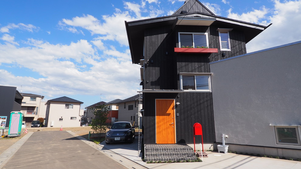 This is an example of a mid-sized transitional three-storey black house exterior in Tokyo with wood siding, a gable roof and a metal roof.
