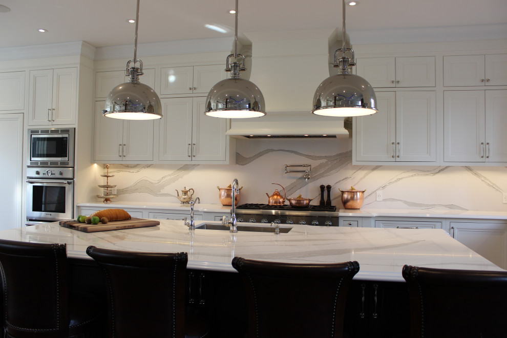 トロントにある巨大なトランジショナルスタイルのおしゃれなキッチン (ダブルシンク、フラットパネル扉のキャビネット、白いキャビネット、クオーツストーンカウンター、白いキッチンパネル、クオーツストーンのキッチンパネル、パネルと同色の調理設備、濃色無垢フローリング、茶色い床、白いキッチンカウンター) の写真