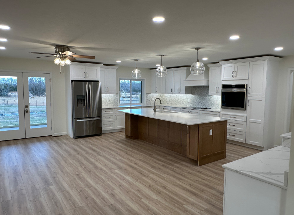 Large transitional u-shaped laminate floor and beige floor eat-in kitchen photo with an undermount sink, shaker cabinets, white cabinets, quartz countertops, multicolored backsplash, marble backsplash, stainless steel appliances, an island and multicolored countertops
