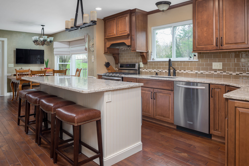 Kitchen - transitional medium tone wood floor kitchen idea in St Louis with an undermount sink, raised-panel cabinets, medium tone wood cabinets, quartz countertops, beige backsplash, glass tile backsplash, stainless steel appliances and an island